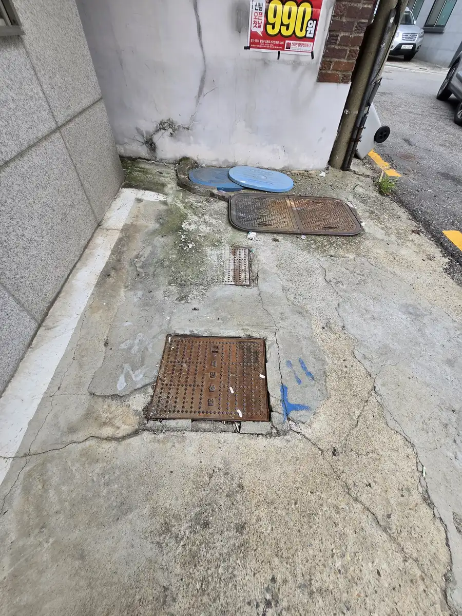 맨홀 뚜껑 교체 이전 균열 있는 바닥, 건물 앞 공간